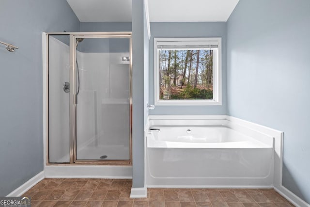 full bathroom with baseboards, a garden tub, and a shower stall