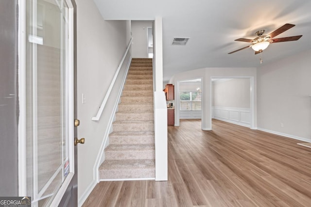 staircase featuring a ceiling fan, wood finished floors, and visible vents