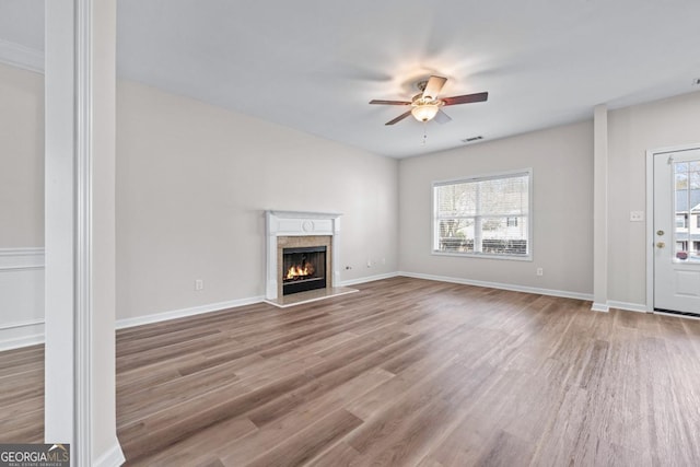 unfurnished living room with visible vents, a healthy amount of sunlight, wood finished floors, and a ceiling fan