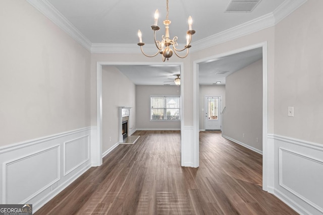 unfurnished living room with dark wood-style floors, visible vents, a warm lit fireplace, and crown molding