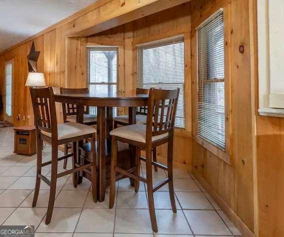 dining room with light tile patterned flooring and wooden walls