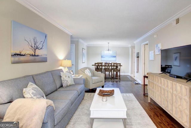 living room featuring a chandelier, visible vents, crown molding, and dark wood-style flooring