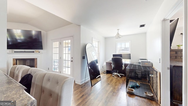 office space with visible vents, lofted ceiling, wood finished floors, a fireplace, and baseboards