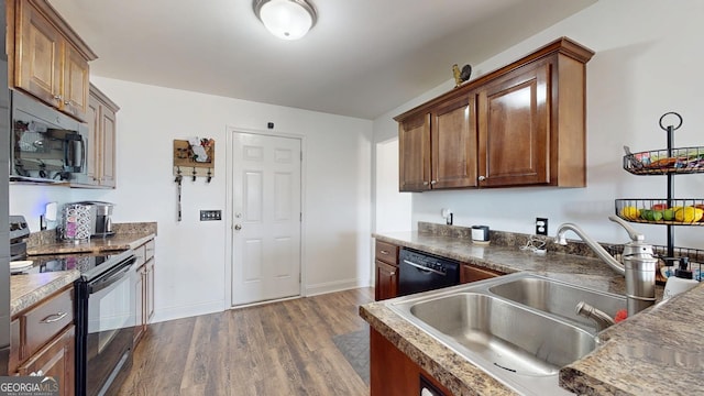 kitchen featuring dark wood-style floors, black appliances, baseboards, and a sink