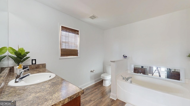 full bath with visible vents, toilet, a garden tub, wood finished floors, and vanity