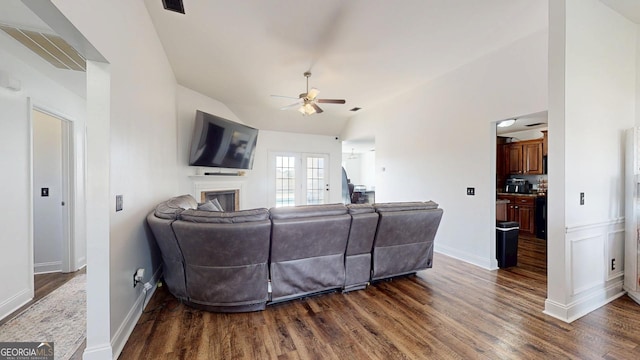 living area featuring a fireplace, dark wood finished floors, a ceiling fan, and vaulted ceiling