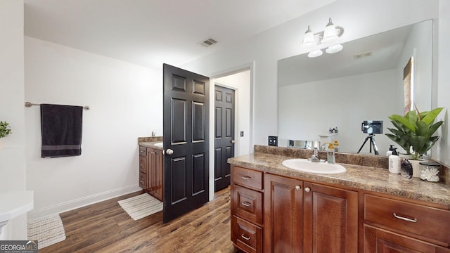 bathroom with visible vents, vanity, baseboards, and wood finished floors