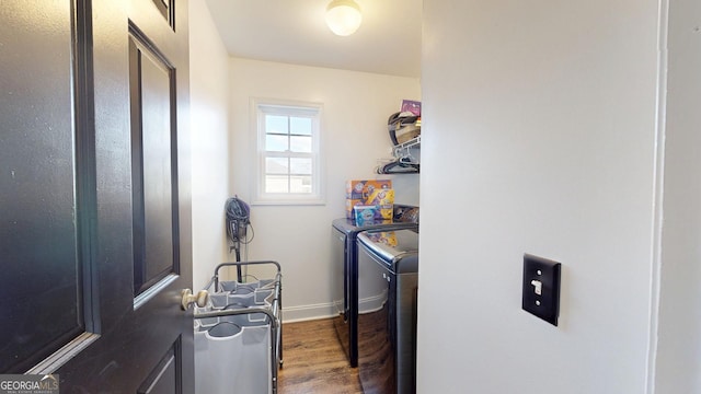 laundry area featuring laundry area, washing machine and dryer, baseboards, and wood finished floors