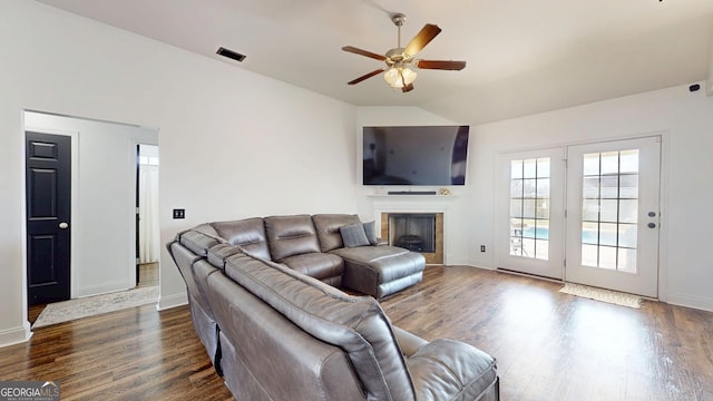 living area featuring dark wood finished floors, visible vents, a ceiling fan, and vaulted ceiling