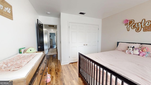 bedroom with a closet, visible vents, and wood finished floors