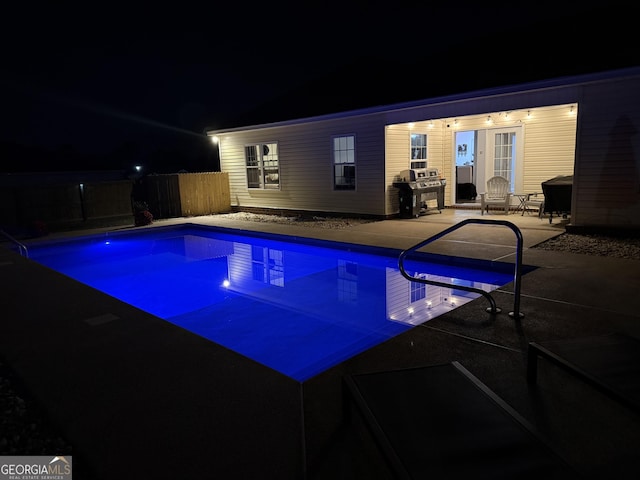 pool at twilight featuring a patio, fence, a fenced in pool, and grilling area