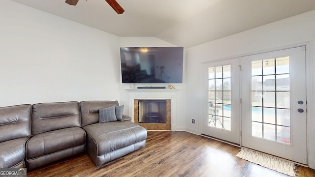 living area featuring vaulted ceiling, a fireplace, ceiling fan, and wood finished floors