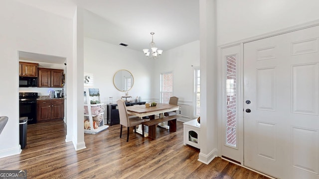 interior space with dark wood finished floors, an inviting chandelier, a high ceiling, and visible vents