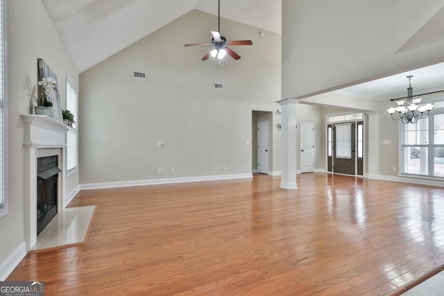 unfurnished living room featuring visible vents, ceiling fan with notable chandelier, light wood-style floors, a premium fireplace, and baseboards