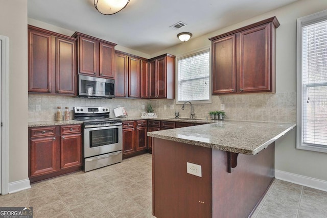 kitchen featuring a wealth of natural light, visible vents, a sink, stainless steel appliances, and a peninsula