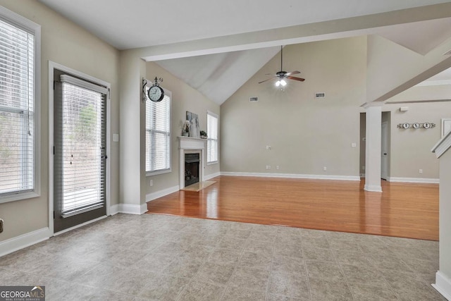 unfurnished living room with wood finished floors, baseboards, decorative columns, a fireplace, and ceiling fan