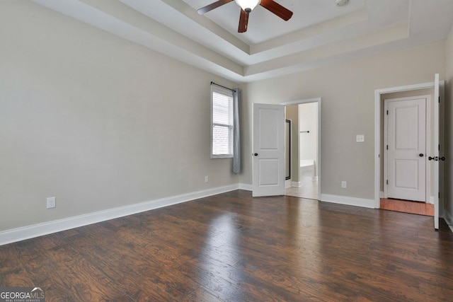 interior space featuring a ceiling fan, a tray ceiling, wood finished floors, and baseboards