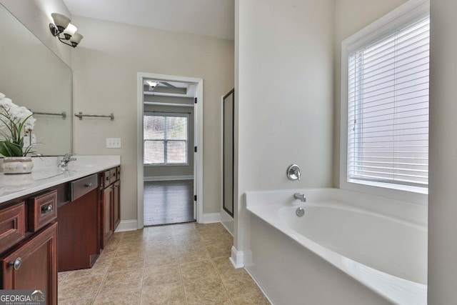 bathroom with a garden tub, a stall shower, tile patterned flooring, baseboards, and vanity