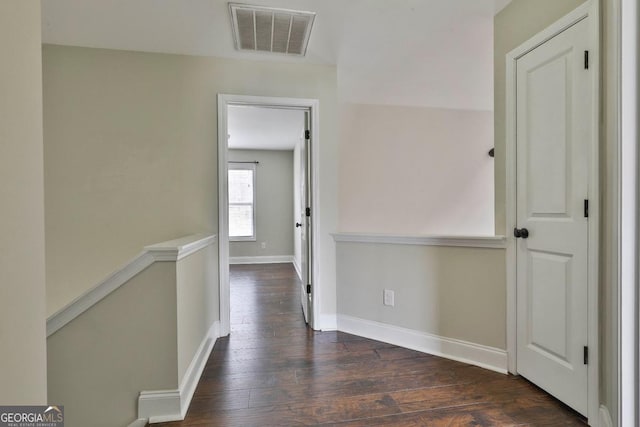 corridor featuring dark wood finished floors, baseboards, and visible vents