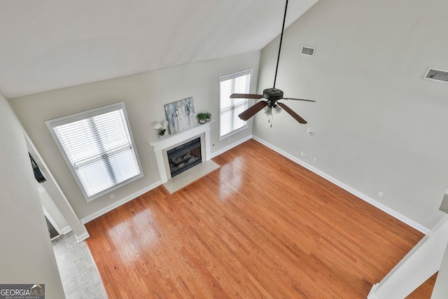 unfurnished living room featuring visible vents, a fireplace with flush hearth, a ceiling fan, and light wood finished floors