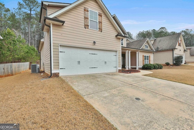 traditional-style house featuring fence, central air condition unit, a front yard, a garage, and driveway