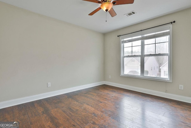 empty room featuring visible vents, baseboards, ceiling fan, and dark wood finished floors