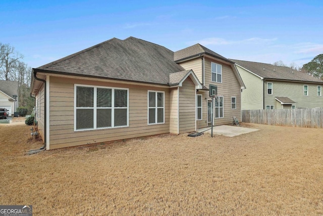 back of property with a patio, roof with shingles, and fence