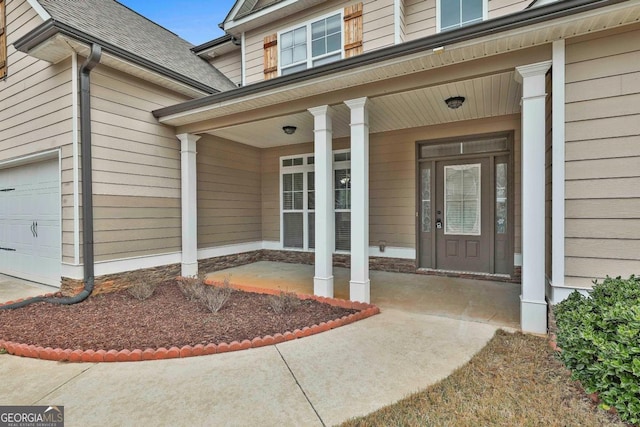 doorway to property with covered porch, an attached garage, and a shingled roof