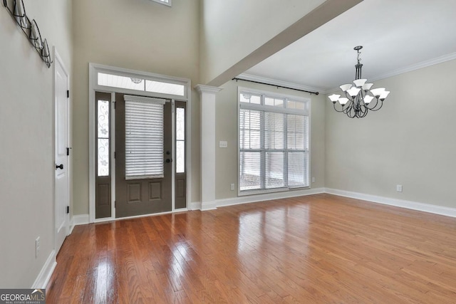 entryway featuring ornamental molding, hardwood / wood-style flooring, a high ceiling, an inviting chandelier, and baseboards