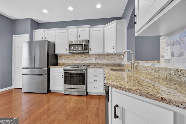 kitchen with white cabinetry, backsplash, appliances with stainless steel finishes, and a sink