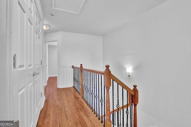 hallway featuring baseboards, an upstairs landing, and light wood finished floors