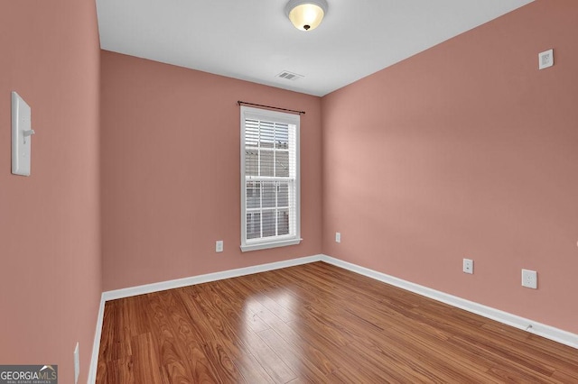 empty room with visible vents, baseboards, and wood finished floors