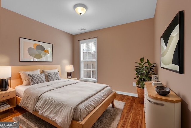 bedroom with wood finished floors, visible vents, and baseboards