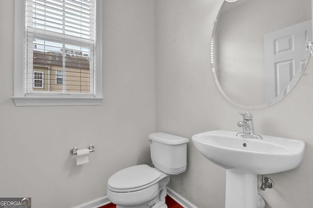 half bathroom with toilet and baseboards