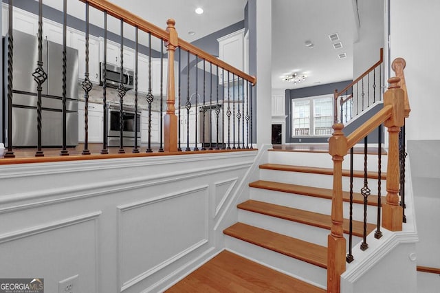 stairs featuring a decorative wall, wainscoting, and wood finished floors