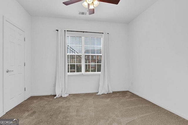 carpeted empty room featuring baseboards, visible vents, and ceiling fan