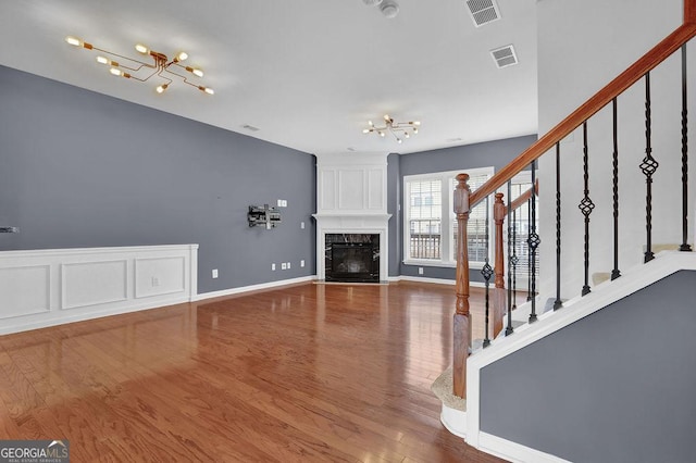 unfurnished living room with visible vents, a notable chandelier, and stairs