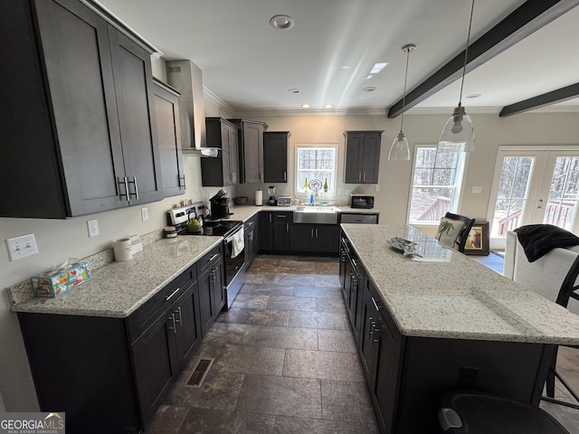 kitchen featuring visible vents, a center island, wall chimney range hood, stainless steel range with electric cooktop, and a sink