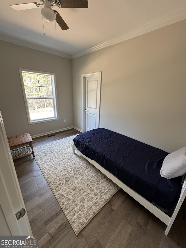 bedroom with visible vents, dark wood-type flooring, crown molding, baseboards, and ceiling fan