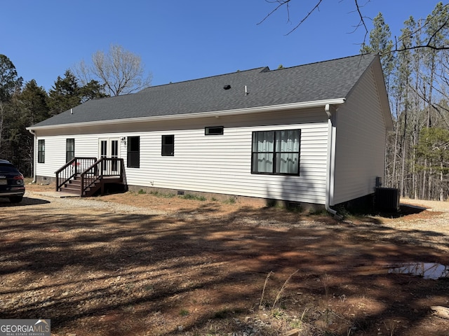 rear view of property with crawl space, central air condition unit, and a shingled roof