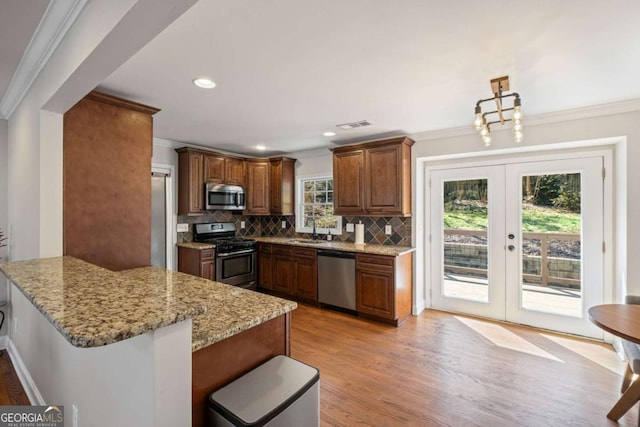 kitchen featuring crown molding, a peninsula, french doors, stainless steel appliances, and a sink