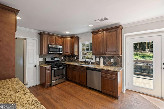 kitchen with visible vents, dark wood finished floors, ornamental molding, stainless steel appliances, and a sink