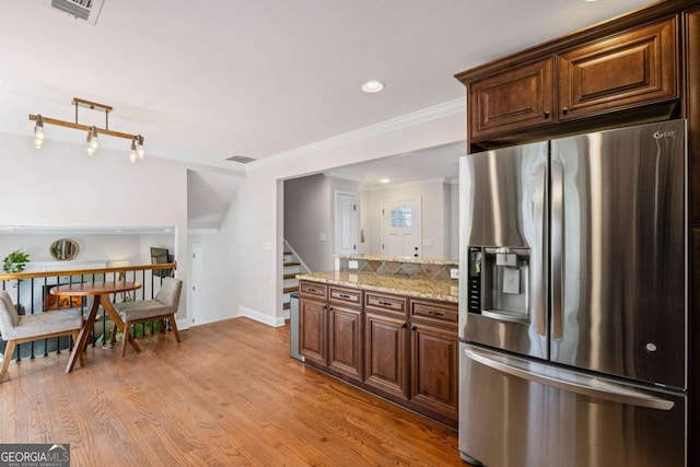 kitchen featuring visible vents, ornamental molding, stainless steel refrigerator with ice dispenser, light wood finished floors, and light stone countertops