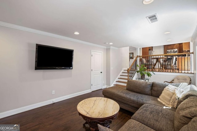 living room featuring visible vents, baseboards, wood finished floors, and crown molding