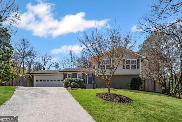 tri-level home with brick siding, a front lawn, fence, a garage, and driveway