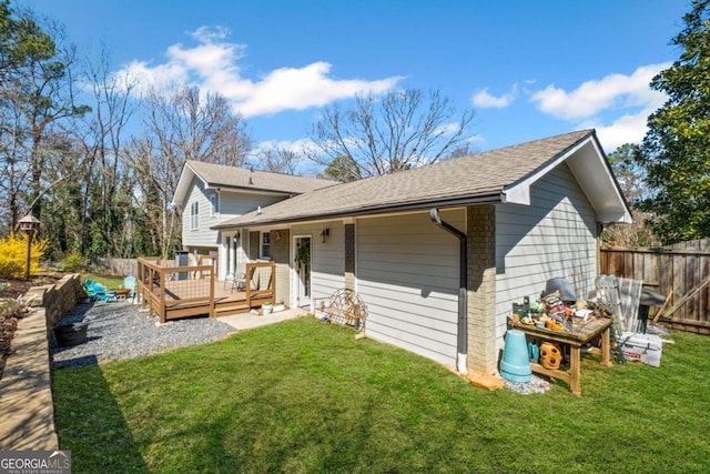 back of house featuring a lawn, a wooden deck, and fence