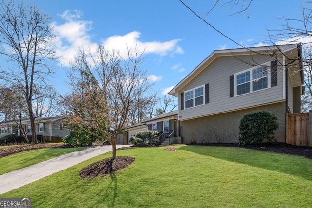 view of front of house with driveway, a front lawn, fence, a garage, and brick siding