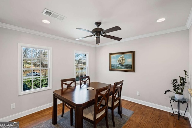 dining room featuring visible vents, baseboards, wood finished floors, and ornamental molding