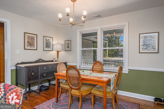 dining area with visible vents, baseboards, an inviting chandelier, and wood finished floors