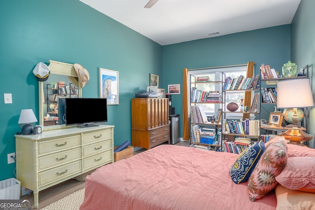 bedroom with ceiling fan, visible vents, and wood finished floors